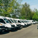 Row of white vans parked in a lot, representing a business vehicle fleet