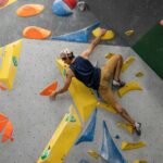 Man bouldering on a climbing wall, tackling a route like those the grades describe