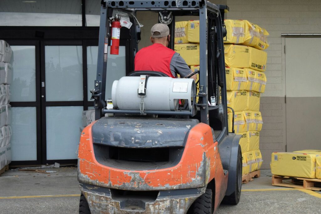 A man driving a forklift in a warehouse, a typical workplace for trained operators