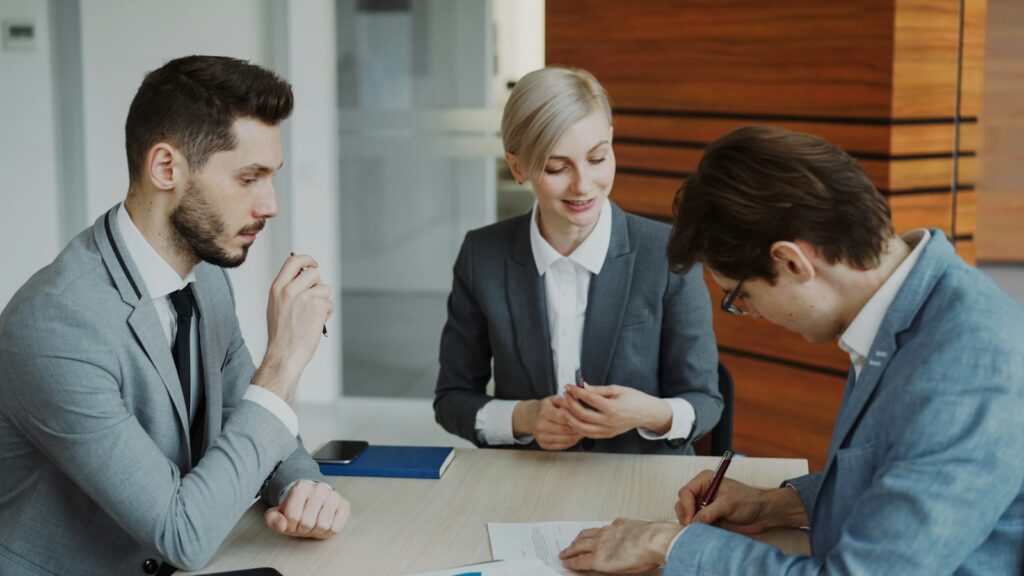 Business people signing a contract at a table, representing agreements in legal finance