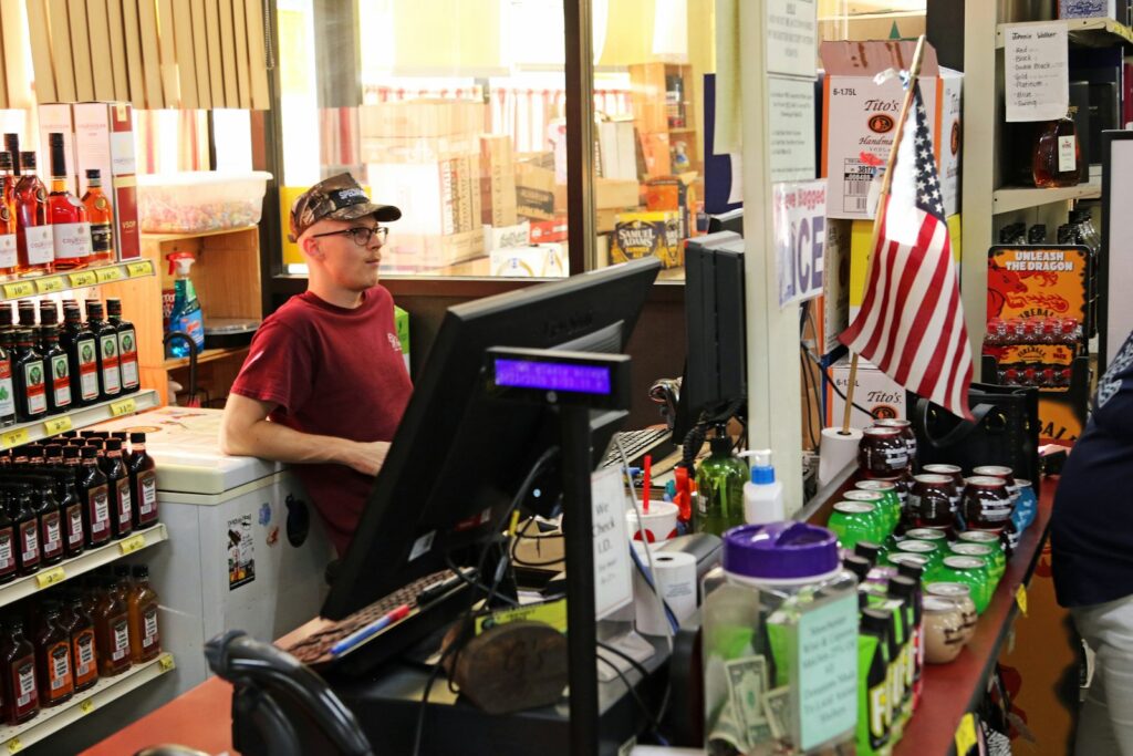 Young man working behind a store checkout counter, representing retail counter work