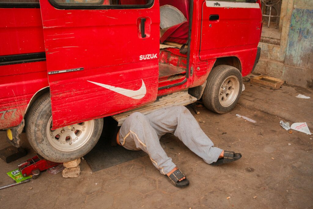 Person lying under a red van carrying out repairs, part of keeping a fleet running