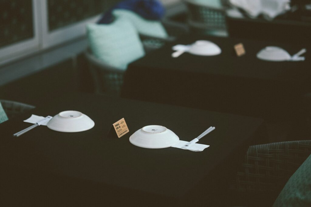 White bowls and chopsticks on black tablecloths in an outdoor restaurant setting