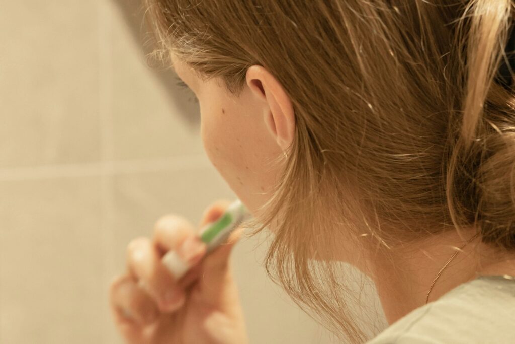 Woman brushing her teeth in front of a mirror as part of a daily routine