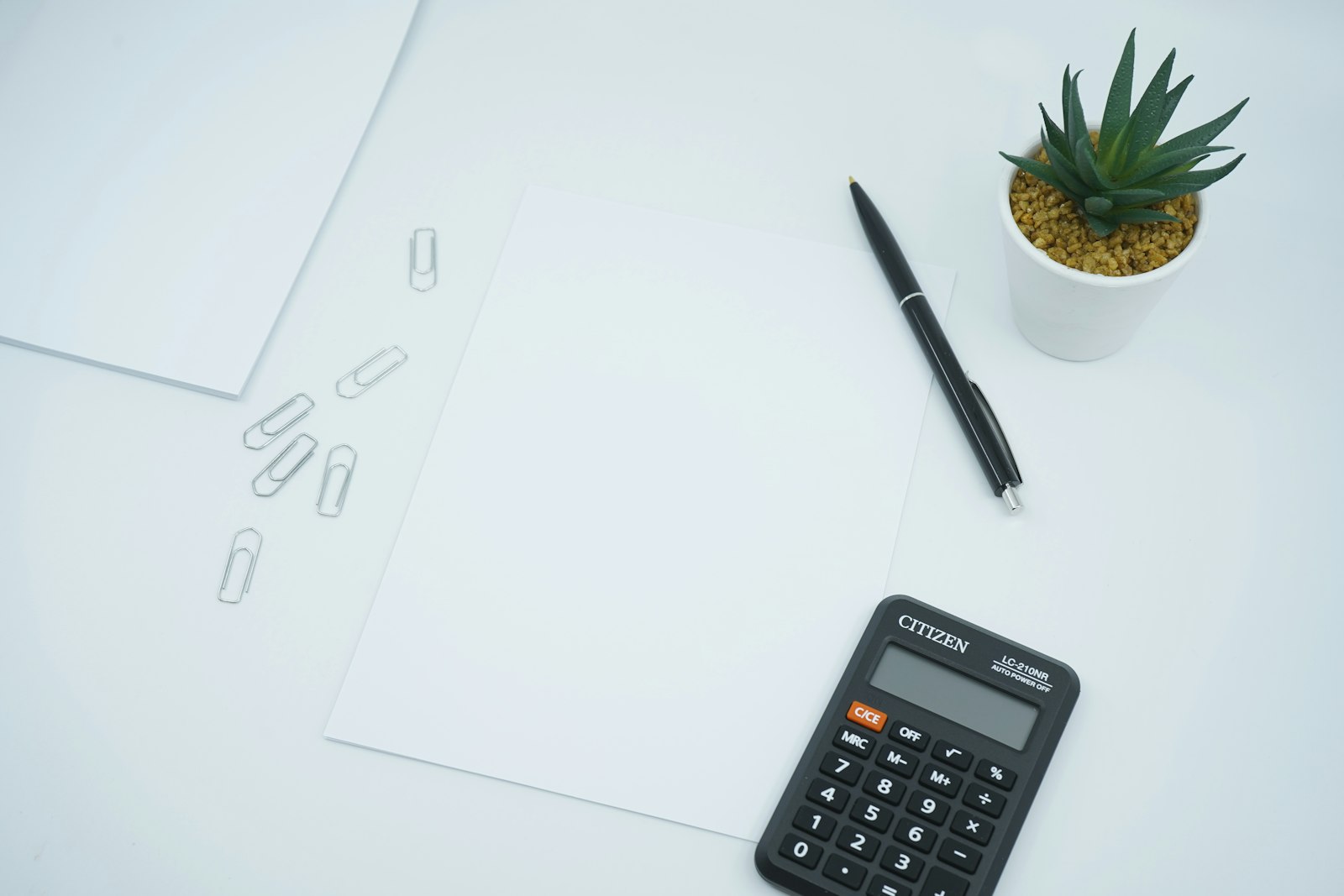 Black calculator beside a black pen on white paper on a desk, ready to crunch numbers